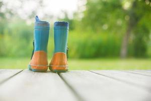 caucho botas en un de madera antecedentes. para niños caucho botas en un antecedentes de verde césped foto