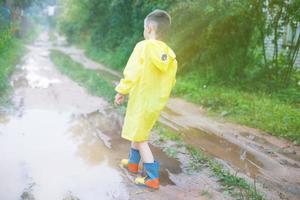 child in rubber boots playing in a puddle photo
