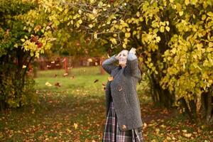 girl in the park throws autumn leaves photo