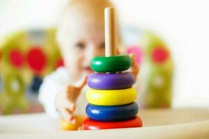 the kid plays the pyramid. child playing with wooden toys photo