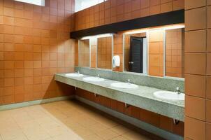 Interior of public clean toilet in a shared toilet there is a wide selection of sinks with mirrors photo