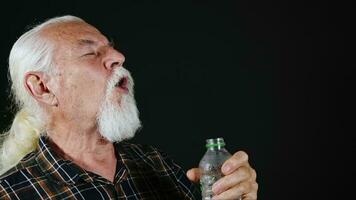 Old White Haired Man is Drinking Water From Plastic Bottle photo