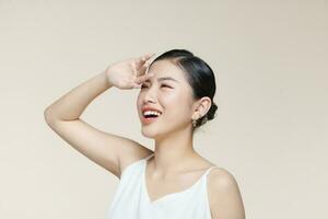 Young asian woman covers her face from the sun with palm against a beige background photo