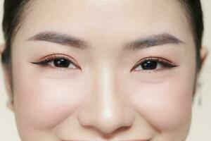 Happy young woman face with clear skin on brown background, closeup portrait photo