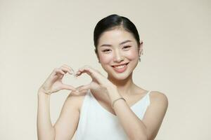 young pretty girl smiling and feeling happy, making heart shape with both hands photo