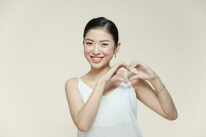 young pretty girl smiling and feeling happy, making heart shape with both hands photo