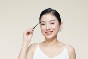 Young girl using brush for eyebrows. photo