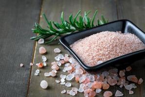 Himalayan Rock pink Salt in black bowl and rosemary leaf photo