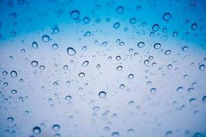 azul agua gotas y gotas de lluvia adherirse a el frio claro vaso foto