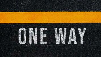 One way text written and yellow line on the road in middle of the asphalt road, One way word on street. photo