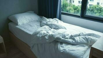Mañana a moderno dormitorio - estropeado cama con blanco cama ropa de cama, hoja, almohadas, frazada, cortinas y ventana. foto