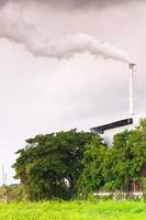 chimenea de fábrica enorme que contamina el aire, chimenea alta que emite vapor de agua y contaminación por humo, industria que causa contaminación foto