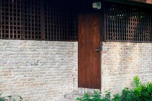 Brown painted vintage wooden door set into left side of old brick wall photo