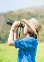 mujer use sombrero y sostenga binocular en el campo de hierba foto