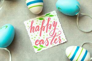 Happy Easter concept. Preparation for holiday. Blue Easter eggs Inscription HAPPY EASTER letters text on concrete stone grey background. Flat lay top view copy space. photo