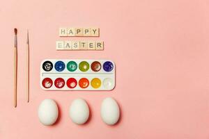 Inscription HAPPY EASTER letters eggs colorful paints isolated on trendy pastel pink background photo