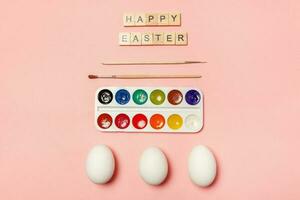 Inscription HAPPY EASTER letters eggs colorful paints isolated on trendy pastel pink background photo