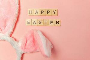 Inscription HAPPY EASTER letters decorative bunny ears isolated on trendy pastel pink background photo