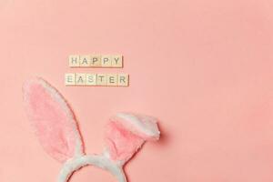 Inscription HAPPY EASTER letters decorative bunny ears isolated on trendy pastel pink background photo