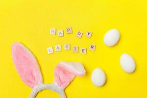 Inscription HAPPY EASTER letters decorative eggs bunny ears isolated on trendy yellow background photo