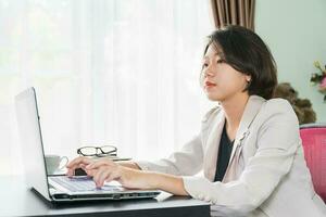 mujer joven en ropa casual inteligente trabajando en la computadora portátil foto