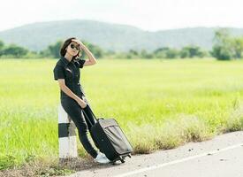 Woman with luggage hitchhiking along a road photo