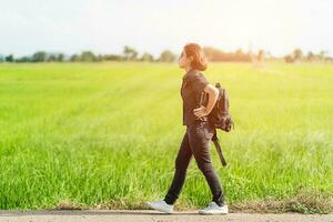 Woman with backpack hitchhiking along a road photo