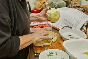 cocinero hace repollo rollos con salmón, zanahorias y salsa en el cocina. francés receta