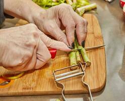 Chef prepares Asparagus in the kitchen on wooden board according to recipe from the Internet photo