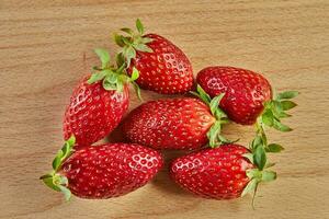 Fresh selected strawberries, stacked in slide on wooden background photo