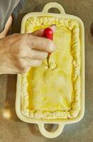 cocinero cortes agujeros en un soufflé hecho desde papas, calabacines, coliflor y amarillo queso foto