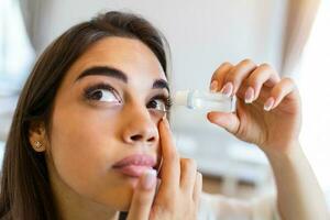 Photo of a woman using eye drop. Female dropping eye lubricant to treat dry eye or allergy. Sick girl treating eyeball irritation or inflammation  sick woman suffering from irritated eye