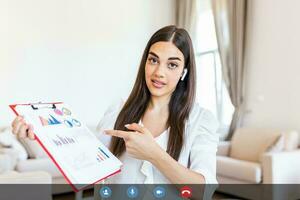 Focused businesswoman presenting charts and graphs on video call online. Young business woman having conference call with client . Closeup business woman working indoor. photo