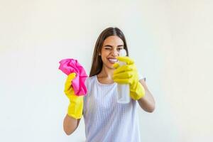 Young woman doing house chores holding cleaning tools. Woman wearing rubber protective yellow gloves, holding rag and spray bottle detergent. It's never too late to clean photo