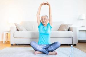 Elderly woman workout before fitness training session at home. Healthy senior woman warming up. She is stretching her arms, smiling and looking away. fitness, sport, training photo