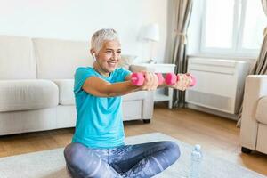 Senior woman exercise with dumbbells at home . happy mature woman doing arm workout using dumbbells. Elderly woman prefers healthy lifestyle photo