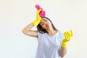 Shot of a young woman looking tired while cleaning at home. Tired young woman standing with cleaning products and equipment, Housework concept. photo