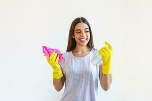 Young woman doing house chores holding cleaning tools. Woman wearing rubber protective yellow gloves, holding rag and spray bottle detergent. It's never too late to clean photo