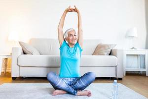 Elderly woman workout before fitness training session at home. Healthy senior woman warming up. She is stretching her arms, smiling and looking away. fitness, sport, training photo