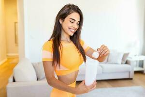 Sport, fitness, healthy lifestyle and people concept - close up of women with jar and bottle preparing protein shake photo