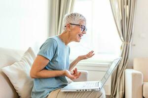 Mature woman explaining something via video call. Gray haired woman feeling happy photo