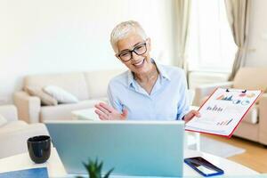 Mature businesswoman presenting charts and graphs on video call online. Middle-aged Business woman having conference call with client on laptop. Closeup business woman working laptop computer indoor. photo