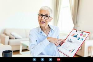 Mature businesswoman presenting charts and graphs on video call online. business, technology and people concept, businesswoman with papers having video conference photo