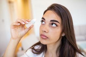 Woman using eye drop, woman dropping eye lubricant to treat dry eye or allergy sick girl treating eyeball irritation or inflammation sick woman suffering from irritated eye, optical symptoms photo