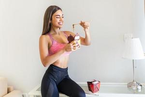 Handsome young woman eating healthy traditional cooked noodles using chopsticks. Beautiful woman enjoying with lunch time. Athlete having a healthy meal after workout photo