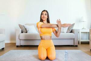 Beautiful Fitness female doing warmup workout at home. Fitness woman doing stretch exercise stretching her arms - tricep and shoulders stretch . Fit girl living an active lifestyle. photo