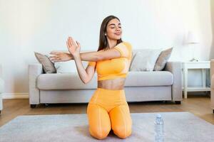 Beautiful Fitness female doing warmup workout at home. Fitness woman doing stretch exercise stretching her arms - tricep and shoulders stretch . Fit girl living an active lifestyle. photo