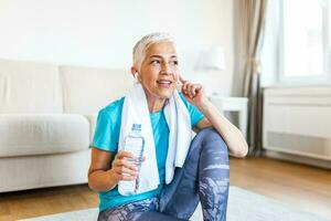 Senior woman with headphones while resting after workout. Athletic mature woman resting after a good workout session photo