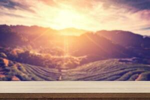 Empty wooden table for product placement or montage and blurred tea field and sunrise vintage. photo