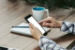 Woman hand holding phone on wooden table at work from home photo